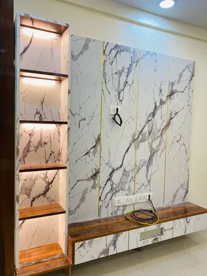 This floating TV unit uses a striking black and white marble laminate with gold-toned metal inlays. The attached vertical shelf has its own backlighting to highlight each compartment.