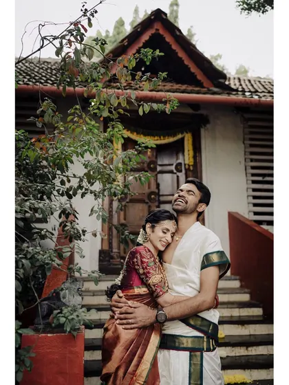 A moment of pure joy and comfort. This portrait captures the couple in a relaxed embrace against a traditional backdrop, their happy expressions telling the story of their love.