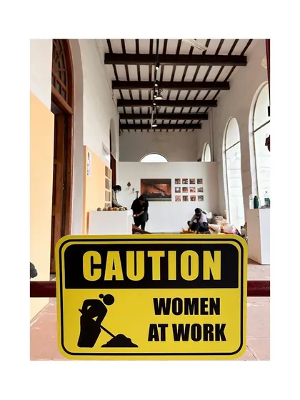 A "Caution: Women at Work" sign at our exhibition space. This sign playfully and powerfully asserts the presence and importance of women in the construction field.