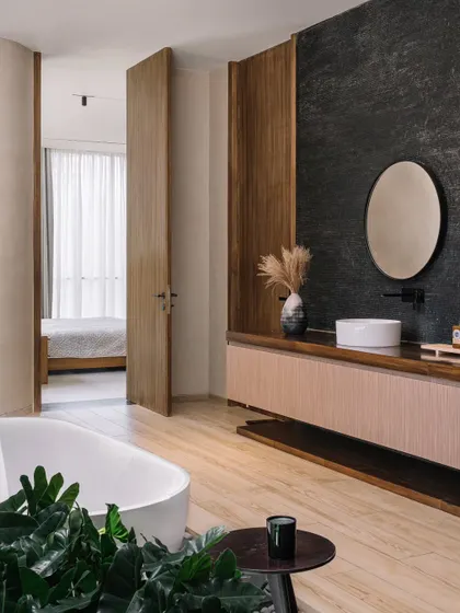 The vanity in the master bathroom features a textured black stone wall and a simple, elegant basin. The design is minimal yet luxurious, focusing on the beauty of natural materials.
