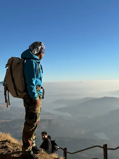 A trekker looks out over the misty valleys from the top of Ratangad. The sense of peace and scale you get from these viewpoints is incredible.
