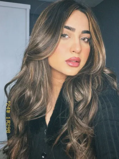A stunning hazelnut brown hair color with highlights. This look is pure glamour, with soft, face-framing waves and a rich, dimensional color.