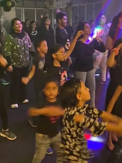 Kids and adults dancing together under the party lights at a studio event. Our community events are for all ages.