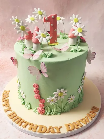 We create an enchanted forest for a first birthday with this magical fairy cake. A lush green canvas is home to whimsical mushrooms, delicate daisies, and fluttering butterflies, creating a storybook setting for a one-year-old's special day.