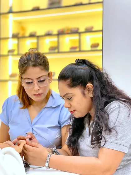 A trainer carefully guides a student's hand, demonstrating the correct technique for using an e-file. We focus on teaching safe and professional practices.