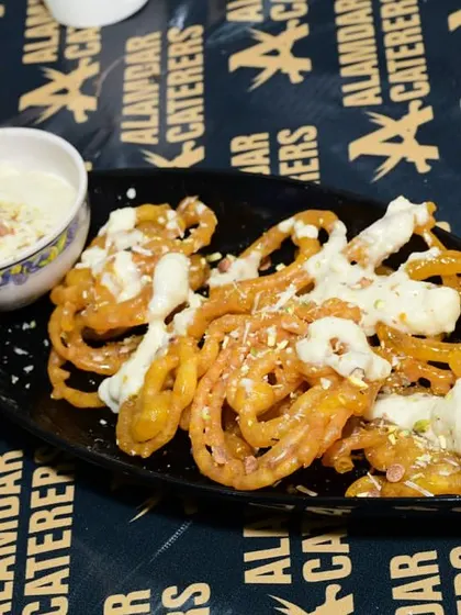 A plate of hot, crispy jalebis topped with creamy rabdi. This classic Indian dessert is a hot seller at our festival.