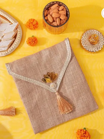 Another view of the jute clutch favor, displayed with traditional Indian sweets and marigold flowers.