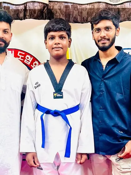 A student proudly poses with his new blue belt.