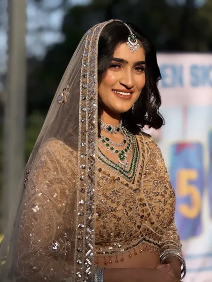 A close-up of the bride's happy face. The simple, elegant hairstyle with a sheer dupatta creates a timeless and sophisticated look.