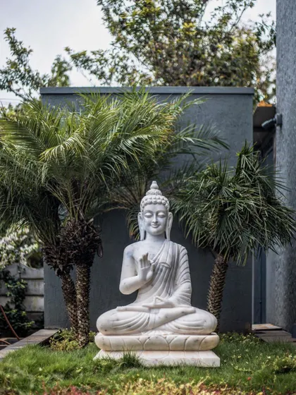 A tranquil corner of the garden featuring a marble Buddha statue, adding a spiritual and calming element to the landscape design.