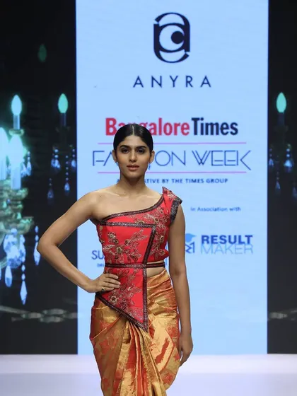 A close-up of the innovative red Kanchi saree look from the runway. The one-shoulder crop blouse is intricately embroidered, offering a modern way to style a traditional silk saree.