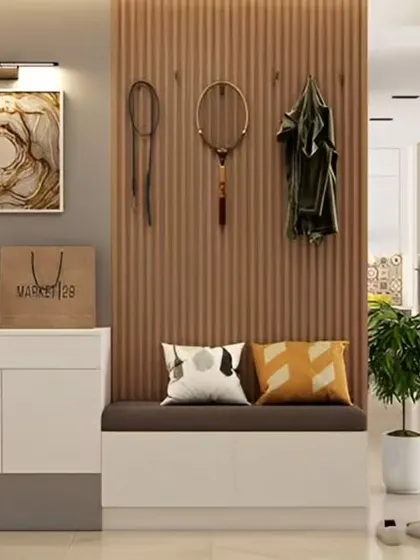 A practical and stylish foyer with a white storage cabinet and a cushioned bench. The slatted wood wall panel includes hooks for hanging coats and accessories.