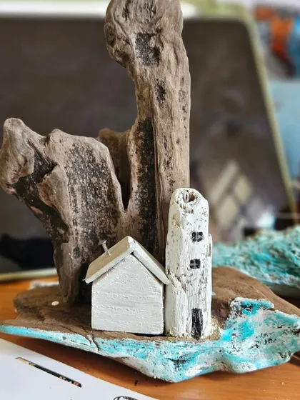 This photo captures a quiet moment in the studio with a driftwood piece mid-creation. We use various small tools to craft the tiny windows and doors on each house.