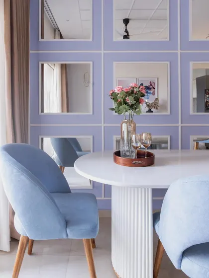 The mirrored grid wall in the dining room is a clever design feature that makes the space feel larger and brighter by reflecting light and the surrounding decor.