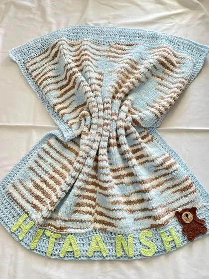 This is our premium "Cuddle Blanket," and it's as soft as it looks. Unlike our other blankets, this one is knitted to create an extra plush and heavy feel. We personalized this one with the baby's name, "Hitaansh," and a small teddy bear appliqué, making it a truly unique newborn gift.