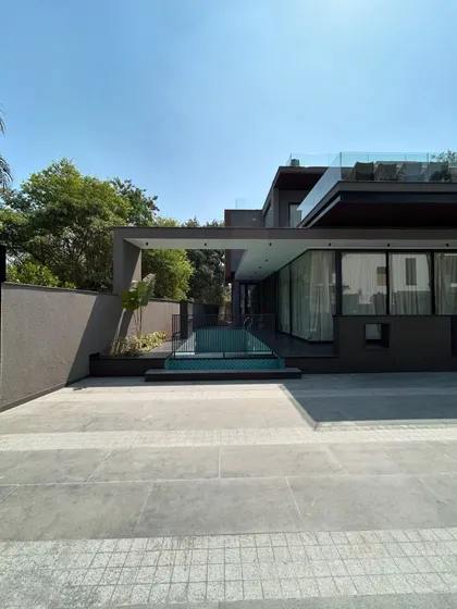 The entrance to the pool at Gulmohar Farmhouse is framed by a modern architectural canopy. This design creates a clear transition from the driveway to the private recreational area, blending functionality with a strong aesthetic statement.