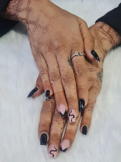 This custom nail art features a striking snake design. The glossy black polish and intricate snake drawings create a powerful and unique look.