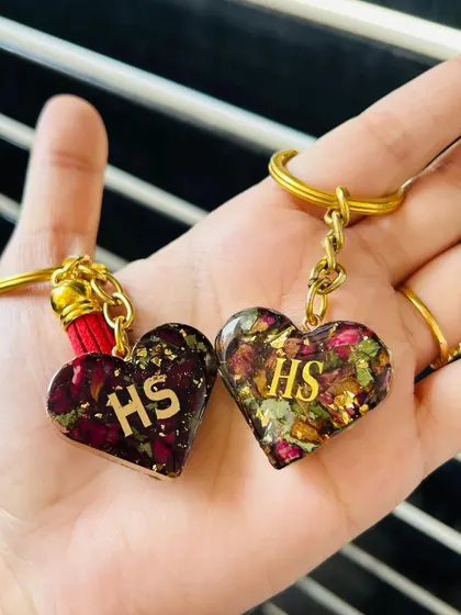 These matching heart-shaped keychains are made with resin and preserved rose petals, personalized with initials. A beautiful and romantic gift for a couple.