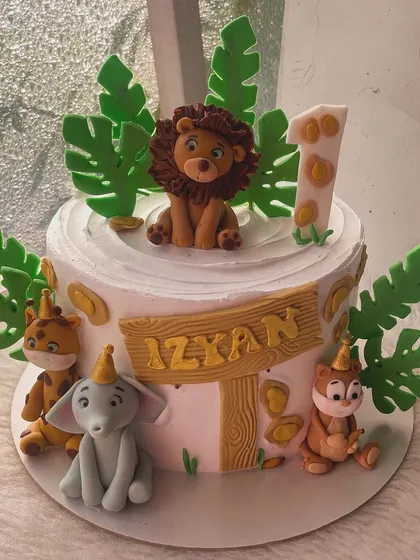 A wild first birthday cake with a classic jungle theme. This design features a friendly lion, elephant, and other animals, all handcrafted from fondant.
