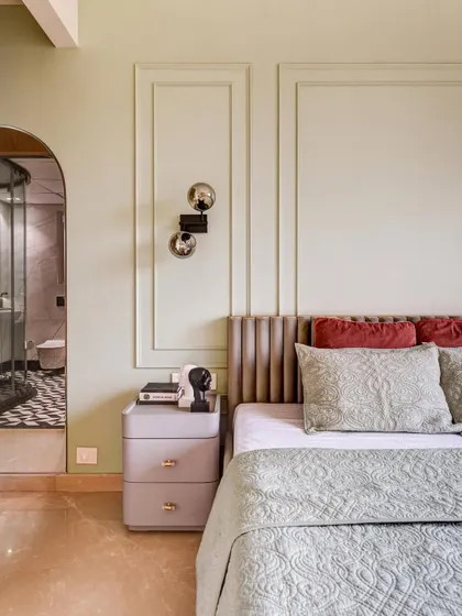 A sophisticated and timeless bedroom design. The soft pastel green wall with classic molding provides a serene backdrop for the upholstered bed, creating a space that feels both elegant and calming.
