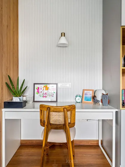 A close-up of the clean and simple study desk, with a cane-back chair and fluted wall paneling.