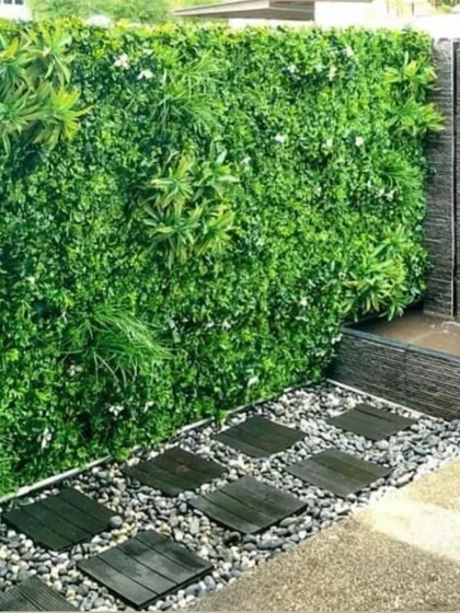 An artificial green wall combined with a modern stepping stone path and pebbles, creating a stylish, low-maintenance garden feature.
