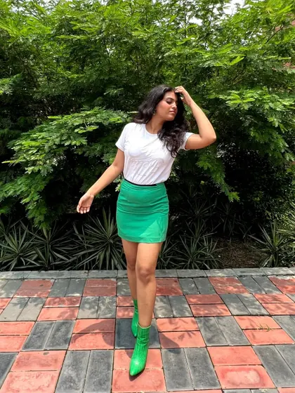 A simple but bold outfit formula: a basic white tee, a vibrant green mini skirt, and matching green ankle boots. This monochrome pop of color is an easy way to elevate a casual look.