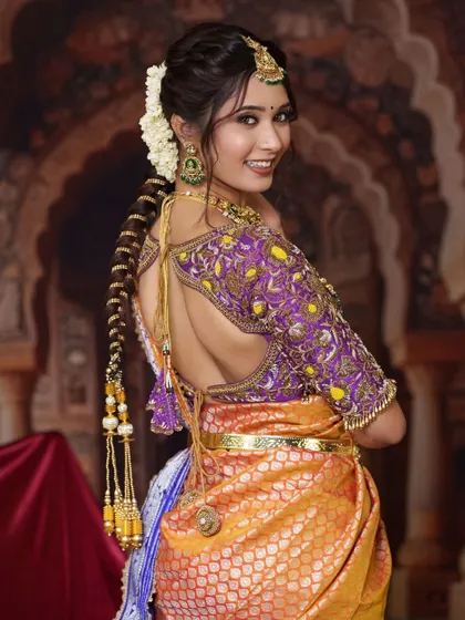 A full view of the bride from the back, showcasing the beautiful hair accessories and the intricate design of the blouse, all tied together by our traditional jewellery.