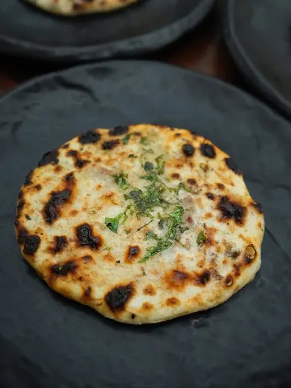 A close-up of one of our freshly baked kulchas, with a charred exterior and a soft, flavourful filling. From blue cheese to bacon, each bite blends bold flavours with culinary finesse.