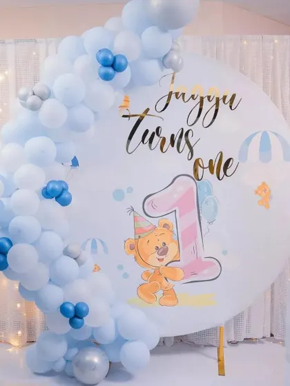 This cute teddy bear theme was for Jujju's first birthday. It features a custom printed circular backdrop with a cartoon bear and the number one, framed by a simple and elegant blue and white balloon arch.
