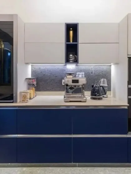 A close-up of a modern kitchen with deep blue handleless cabinets and integrated stainless steel appliances.