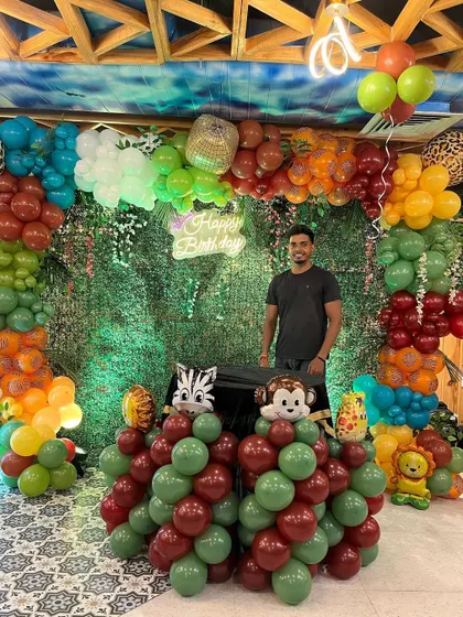 Proudly standing by the finished jungle-themed birthday decoration.