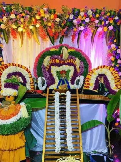 An elegant and colorful backdrop for a deity, made entirely of fresh flowers arranged in intricate patterns.