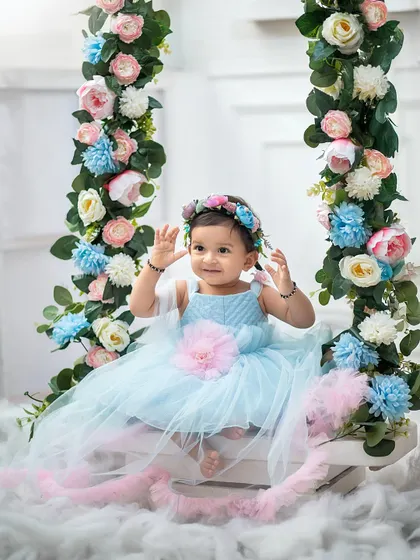 Waving hello from her floral wonderland. This swing, decorated with beautiful pastel flowers, is one of our most popular props for sitter sessions.