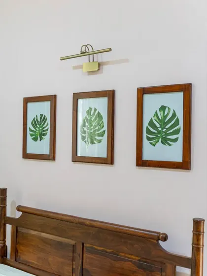 Another angle of the leaf-print artwork above the bed, highlighting the picture light that illuminates them.