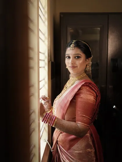 A beautiful portrait of the bride by the window. The natural light highlights the flawless HD makeup and the soft glow on her skin.