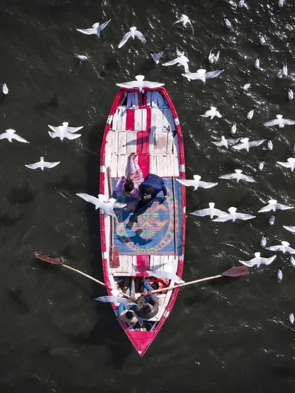 A top-down drone view of a couple's pre-wedding shoot at the Sangam in Prayagraj, surrounded by birds. This unique aerial perspective creates a truly memorable and artistic photograph.