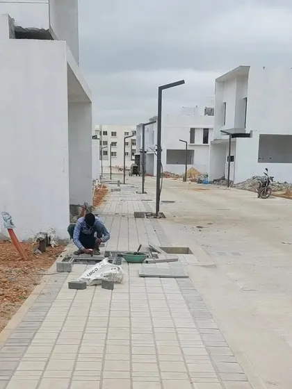 A craftsman carefully lays interlocking paver blocks for a new sidewalk. We oversee every detail of the construction phase to ensure the quality of execution matches the precision of our landscape architecture plans.