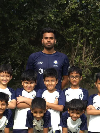 A coach with his young team. This photo captures the mentorship and guidance that is at the heart of our coaching philosophy, building the next generation of players.