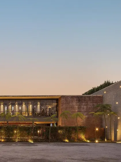 The exterior of Zero40 Brewery at sunset, showing the warm lighting on the brick facade and the surrounding landscape. The design creates a welcoming and atmospheric approach to the building.