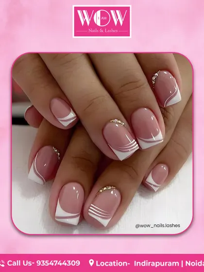 A modern, graphic take on the French manicure. This design features sharp white lines and delicate rhinestone accents on a glossy, natural-looking base.