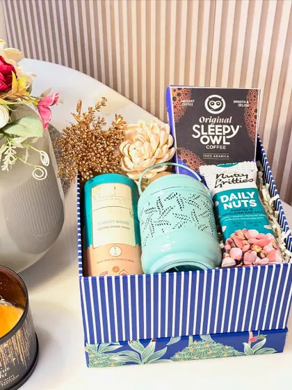 The "Royal Indulgence" box is a perfect Diwali treat. This festive blue box contains Sleepy Owl coffee, a beautiful lantern, a pack of premium nut mix, and incense cones.