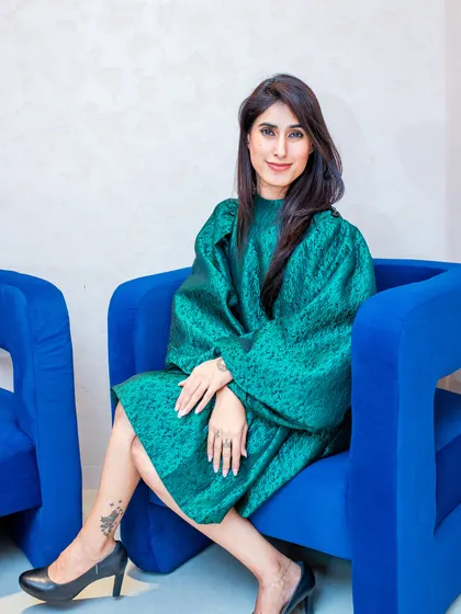 Have you ever noticed how someone can light up a room just by how they carry themselves? In this shot, I'm seated in a vibrant blue chair wearing a structured green dress, demonstrating how good posture creates an image of confidence and elegance even when you're not standing.