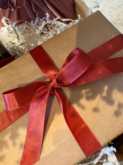 A simple, beautifully wrapped gift box tied with a red satin ribbon, ready to be included in a Valentine's Day surprise.