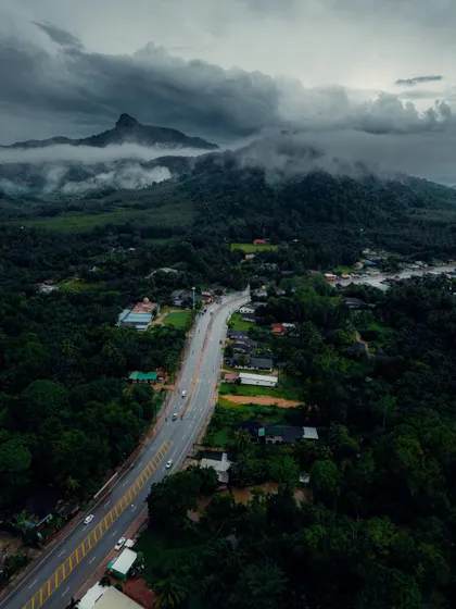 An aerial view of a highway cutting through the lush green landscape of Krabi, with dramatic mountains in the background.
