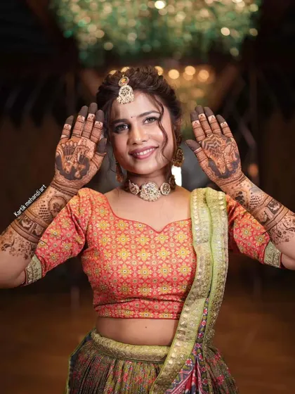 A radiant bride with a big smile, showing her palms adorned with our beautiful mehandi.