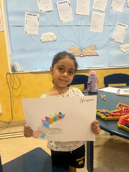 A student shows off her colorful drawing from our science camp. We integrate art into our STEM lessons to encourage creative thinking.