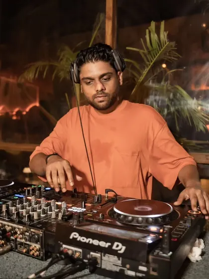 A close up of me working the Pioneer DJ console during an evening set. The warm lighting and relaxed setting are typical of my sundowner gigs.