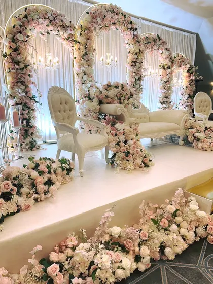 A beautiful stage setup with cascading pink and white florals over multiple arches for a romantic reception.