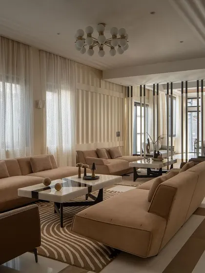 The living area is designed with a palpable synergy between architecture and interior design. Sleek furniture, soft upholstery, and a striking center table create a serene yet sophisticated ambiance.